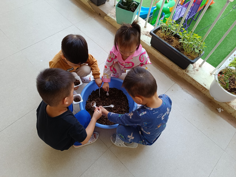 A group of children playing with a spoon in a blue bowl

Description automatically generated